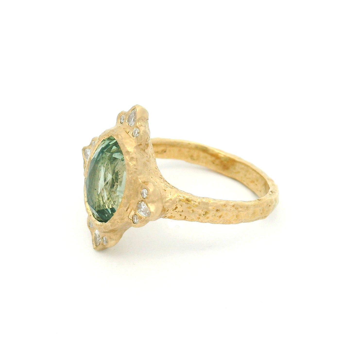 14K yellow gold organic engagement ring with a natural 4.2ct oval mint green sapphire, pear and round diamond accents, and a textured bezel-set design.