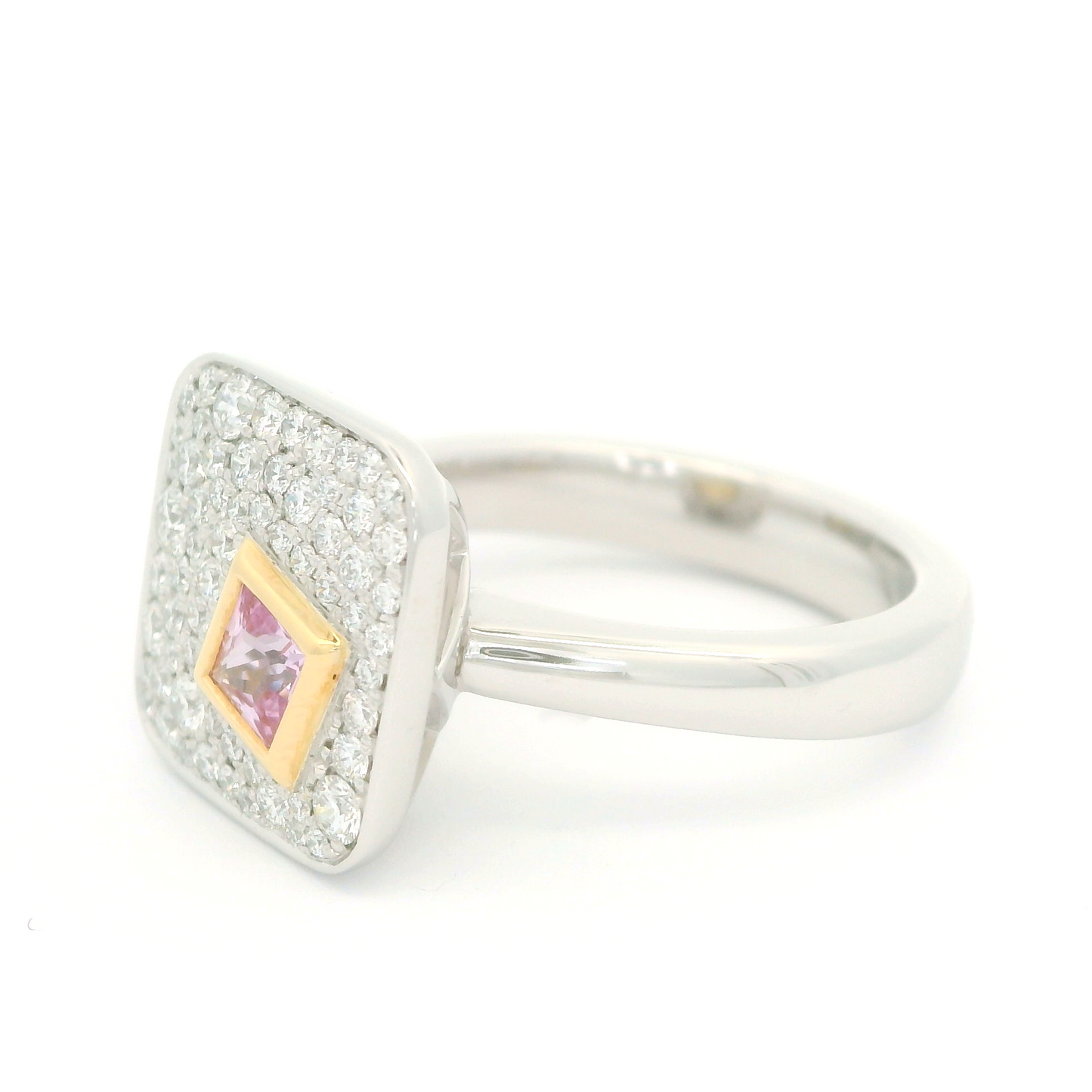 Plat and 18k yellow ring with bezel set 0.25ct pink princess cut sapphire surrounded by pave set diamonds. Shown from an angle.