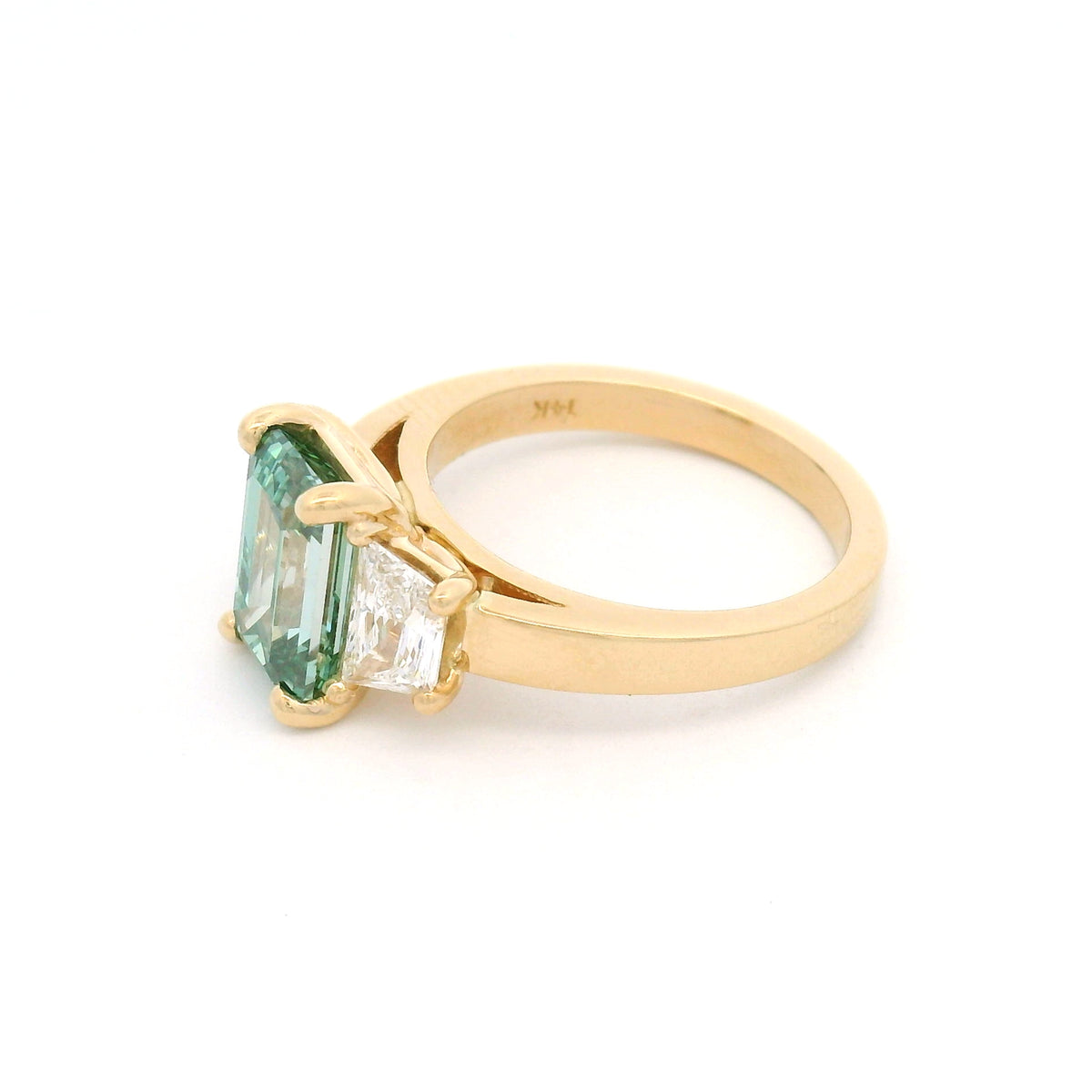 14K yellow gold three-stone engagement ring featuring a claw-set 2.50ct lab-grown green emerald-cut diamond flanked by two lab-grown trapezoid diamonds totalling 0.95cts.