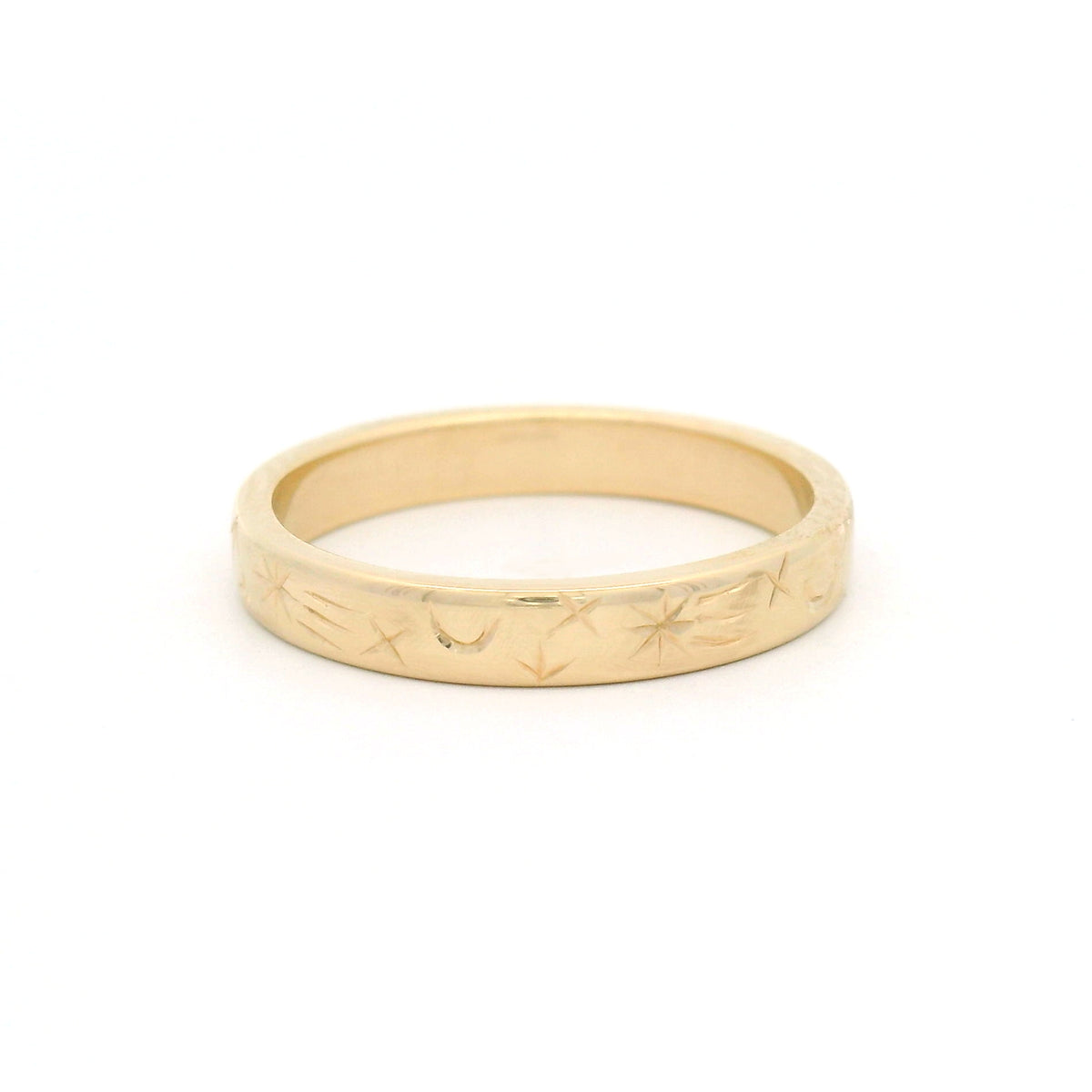 14K yellow gold 3mm flat band featuring intricate hand-engraved celestial star and moon motifs flowing across half the ring.