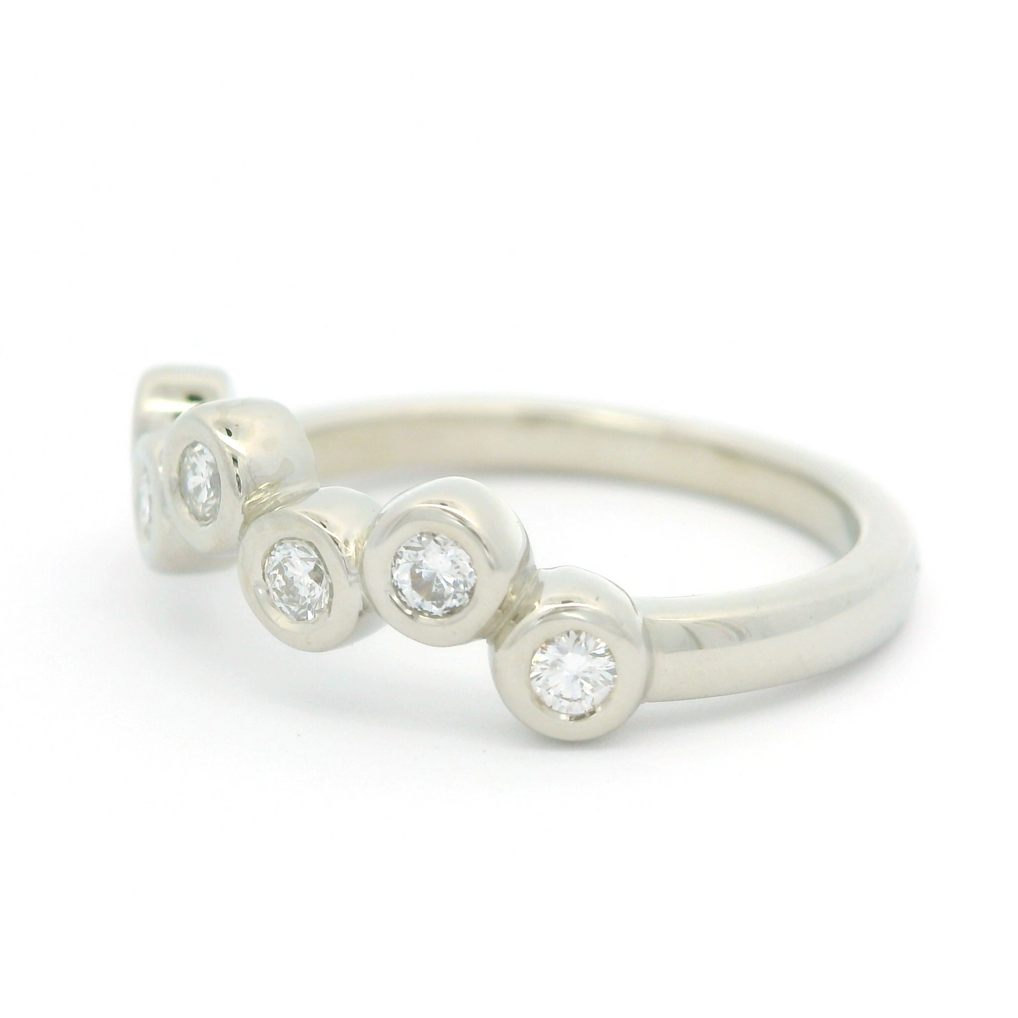 14k white band with seven bezel set diamonds. Shown from an angle.
