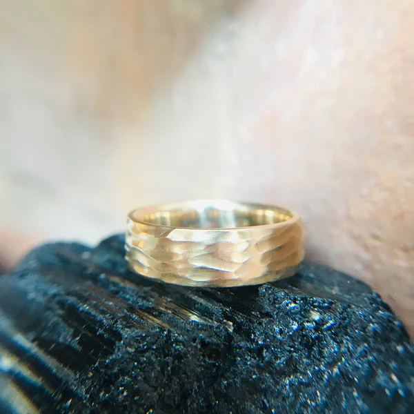 14k Yellow Hand Carved Textured Wedding Band. Shown displayed on a dark crystal.