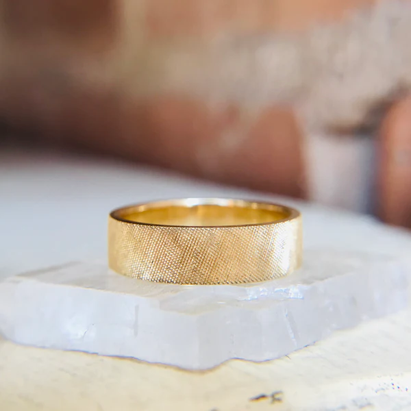 14k Yellow gold band with matte Florentine finish. Canadian. Displayed on a large white crystal.