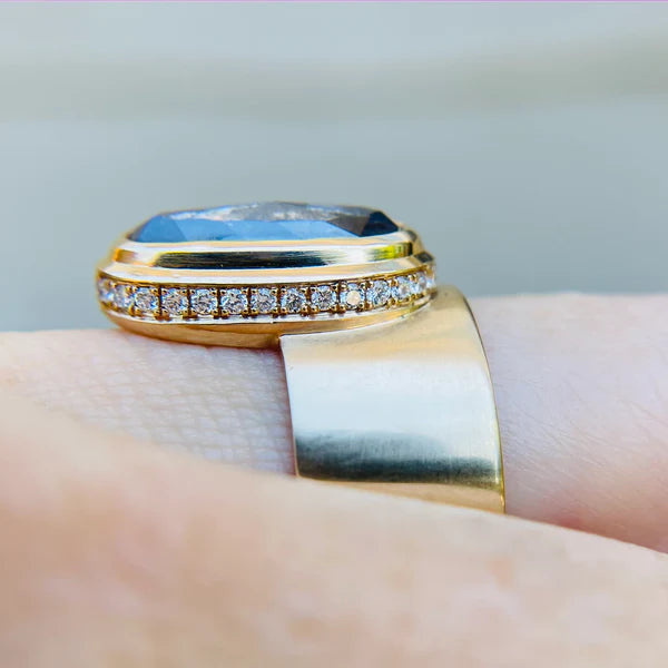 14k yellow gold ring set with a 3.18ct salt and pepper elongated oval rose cut diamond. Shown worn on a finger from the side highlighting the hidden diamonds.