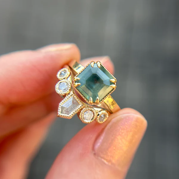 14k-yellow-gold-fancy-white-shield-cut-diamond-quintet-rosecut-contour-band-engagement-ring. Held in hand with a engagement ring.