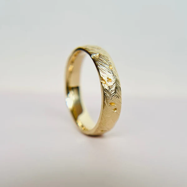 Hand Carved Band, 6mm wide, half round crafted in 14K Yellow. Shown balanced on its side.