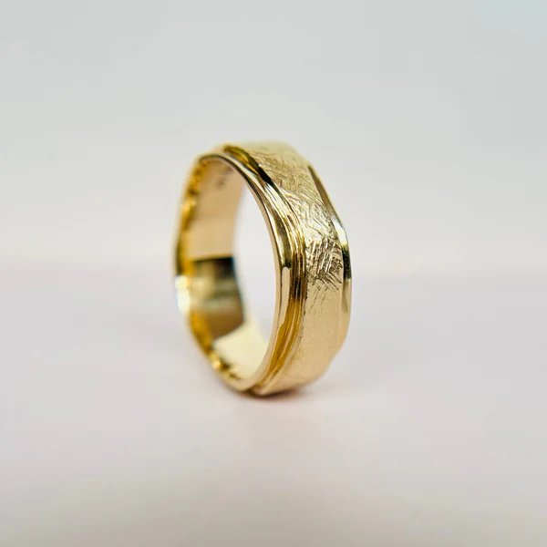 14k Yellow Gold Band Hand Carved with Textured Ribbon. Displayed standing on its edge.