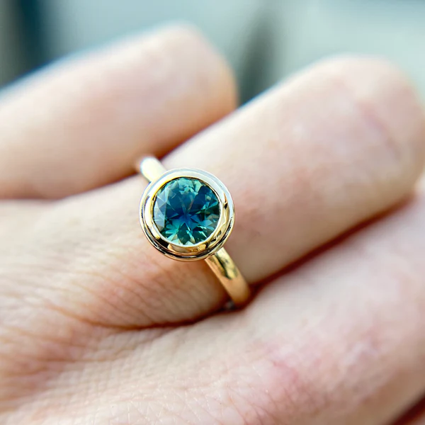 14k Yellow gold round teal sapphire Canadian engagement ring. Worn on hand