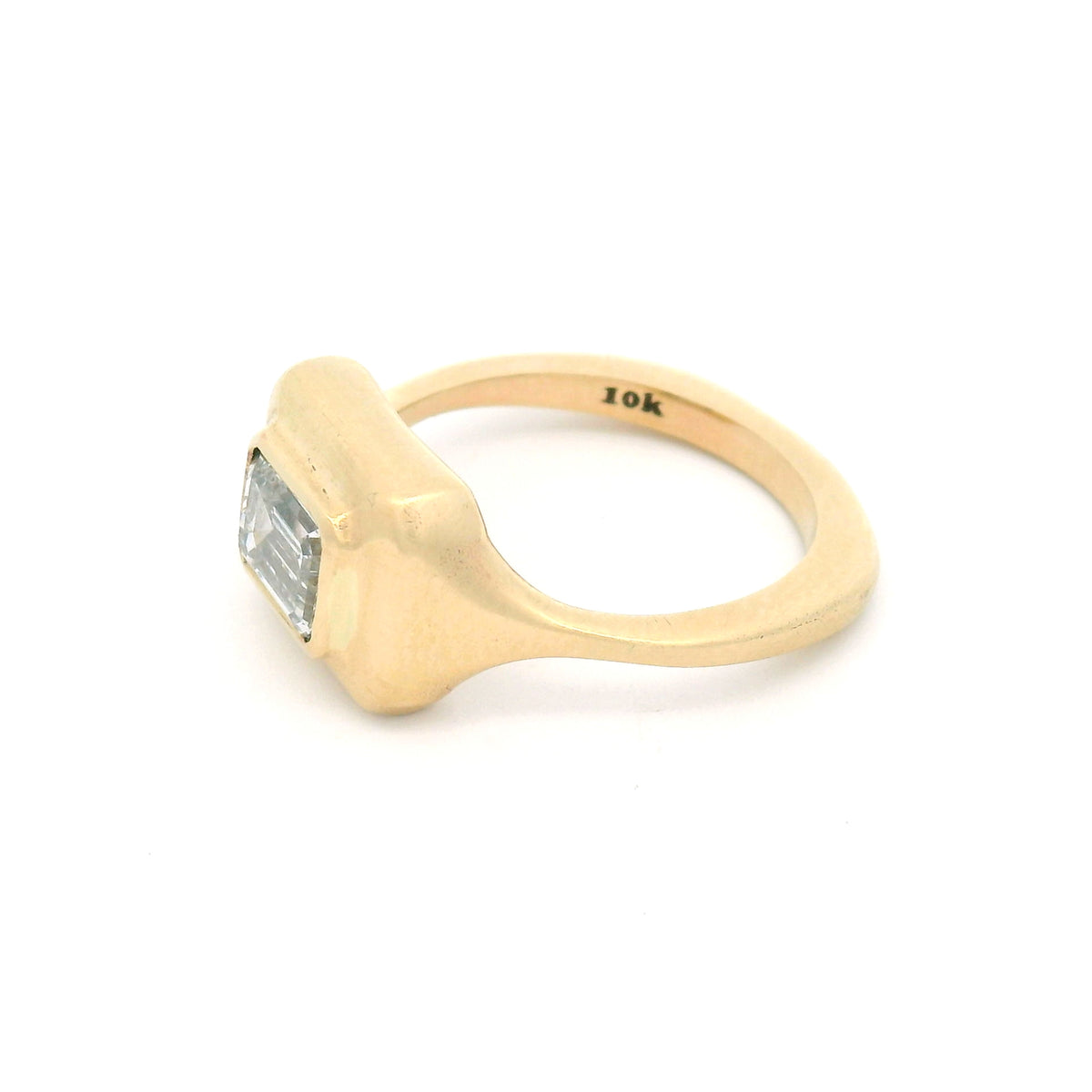 10K yellow gold bezel-set solitaire engagement ring with a 1.02ct lab-grown emerald-cut diamond, VVS2 clarity, D colour and satin-finished sculpted setting.