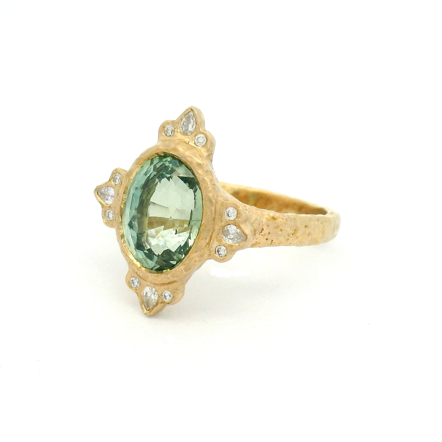 14K yellow gold organic engagement ring with a natural 4.2ct oval mint green sapphire, pear and round diamond accents, and a textured bezel-set design.