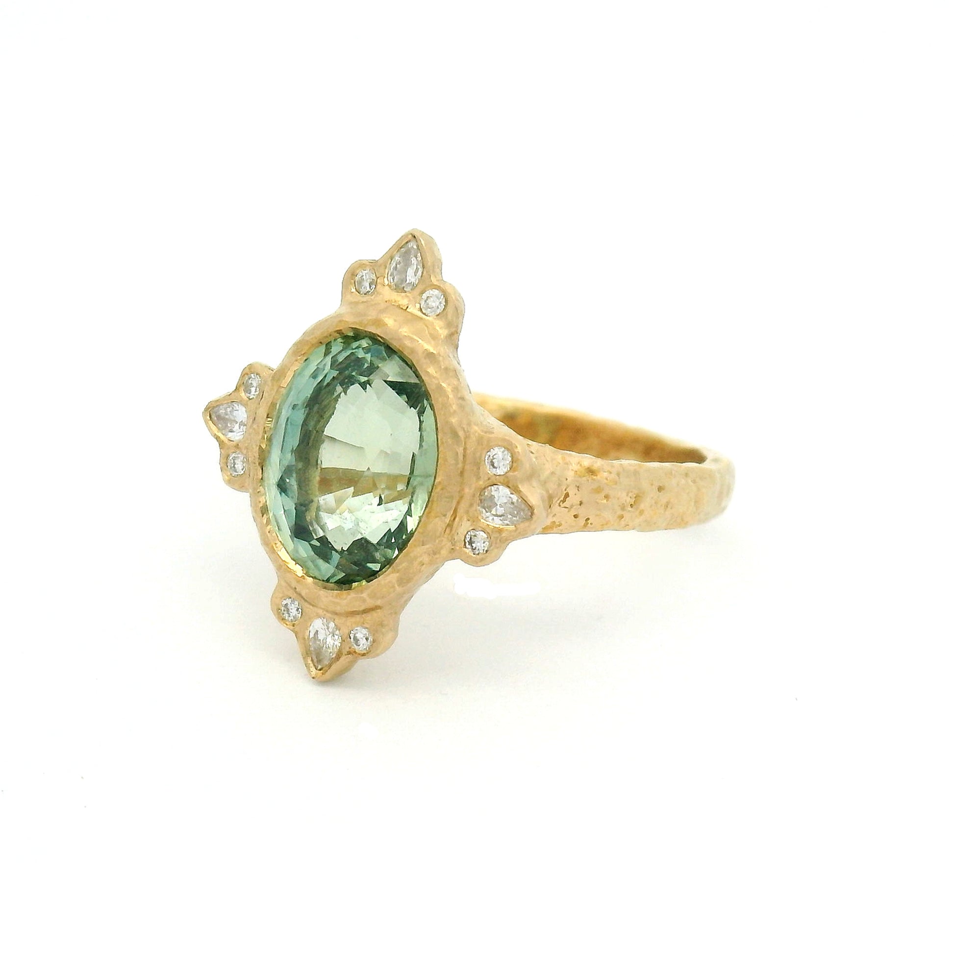 14K yellow gold organic engagement ring with a natural 4.2ct oval mint green sapphire, pear and round diamond accents, and a textured bezel-set design.