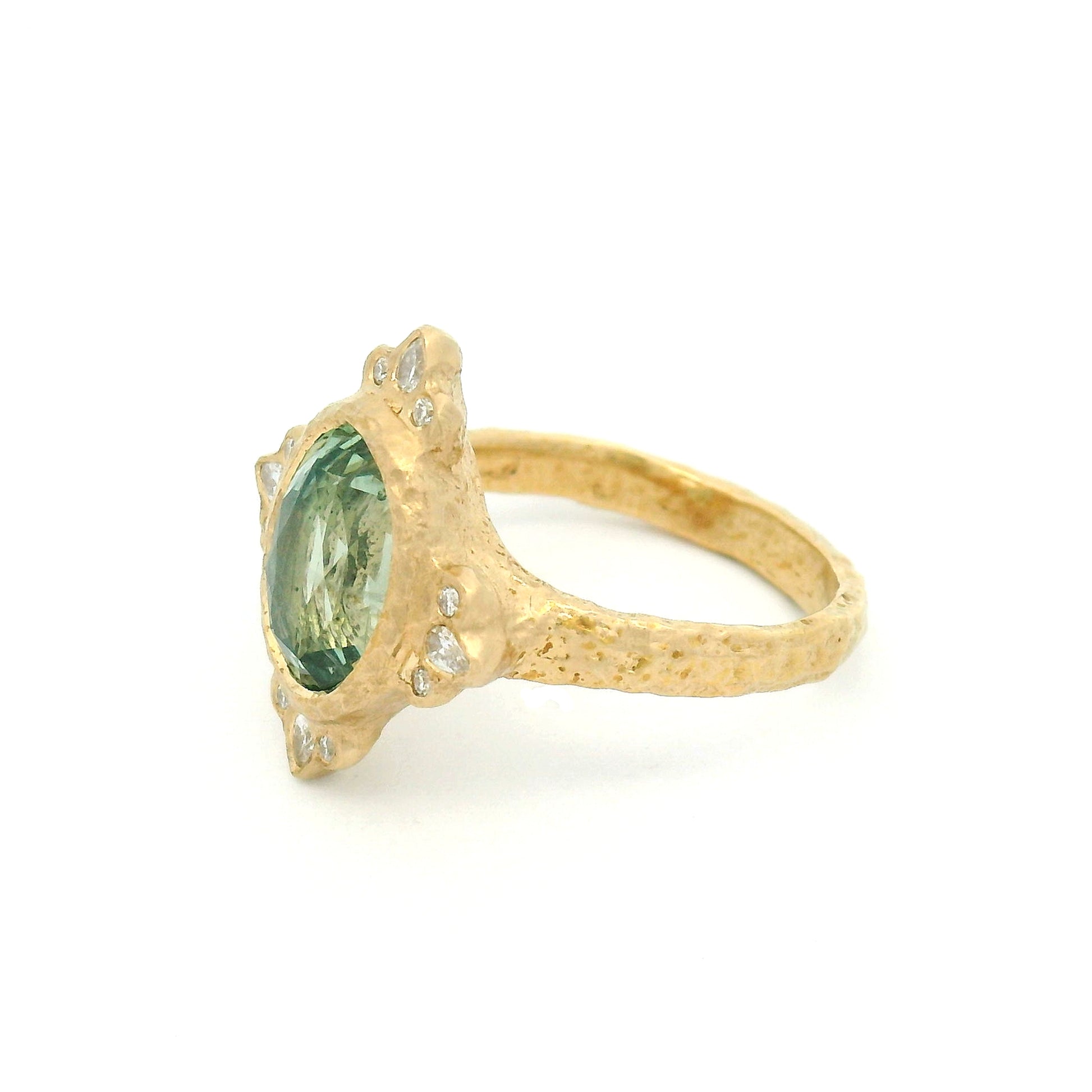 14K yellow gold organic engagement ring with a natural 4.2ct oval mint green sapphire, pear and round diamond accents, and a textured bezel-set design.