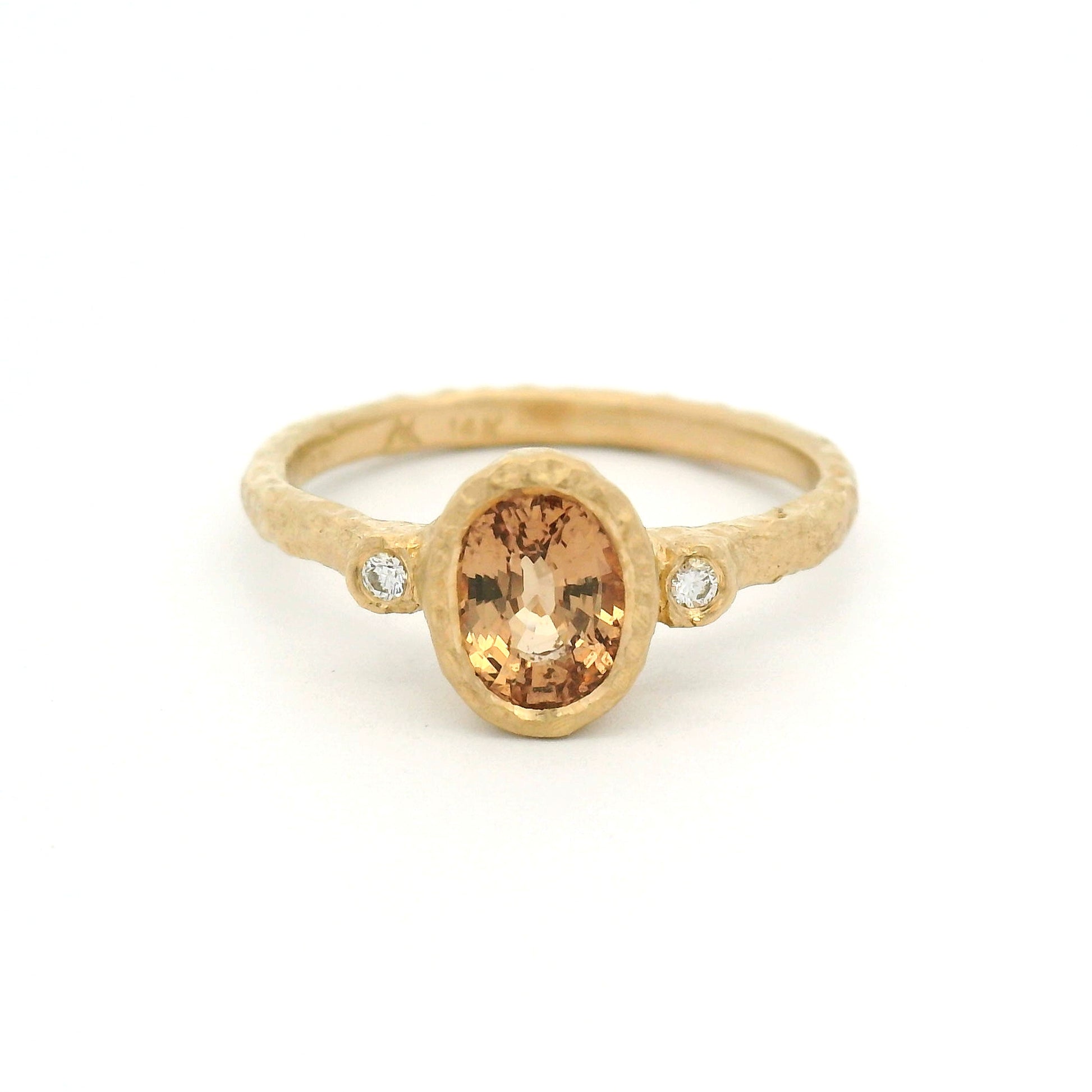 14K yellow gold organic textured engagement ring with bezel-set 1.11ct oval peach sapphire and two bezel-set natural diamond accents.