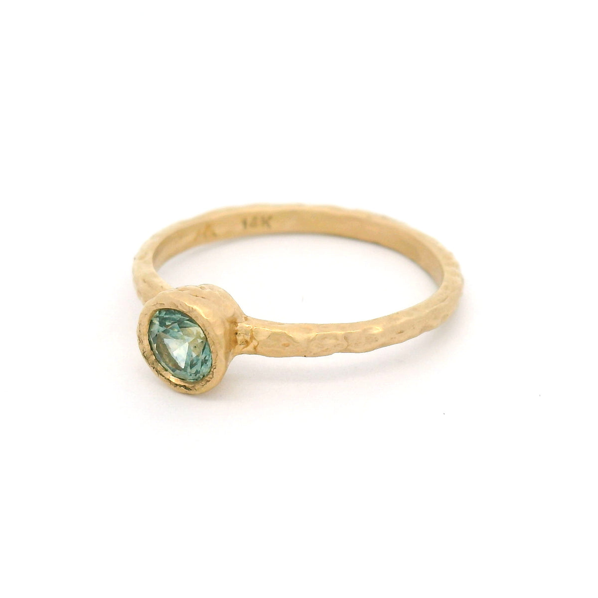 14K yellow gold organic hammered solitaire ring featuring a bezel-set 0.44ct round teal sapphire.