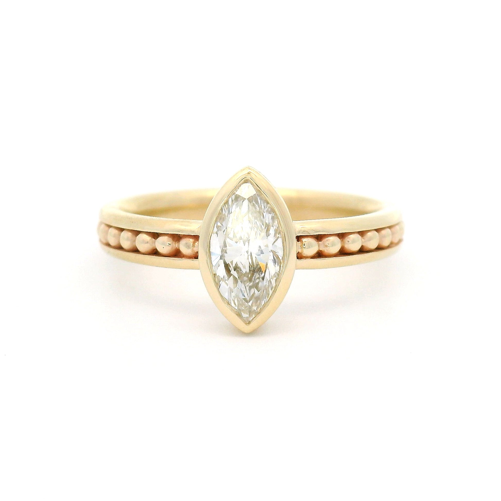 10K yellow gold solitaire engagement ring with a bezel-set 0.70ct lab-grown marquise-cut diamond and delicate gold bead accents within channel details along the band.