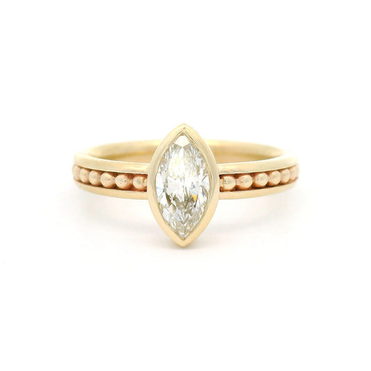10K yellow gold solitaire engagement ring with a bezel-set 0.70ct lab-grown marquise-cut diamond and delicate gold bead accents within channel details along the band.
