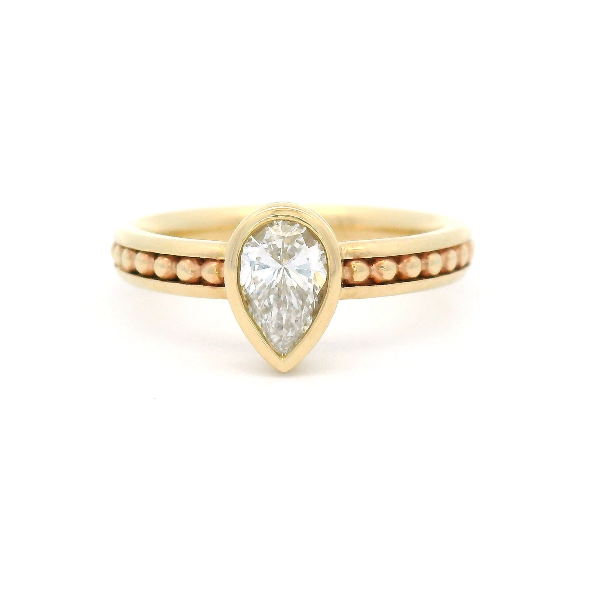 10K yellow gold solitaire engagement ring with a 0.54ct lab-grown pear-shaped diamond, delicate gold bead accents, and channel-set detailing along the band.