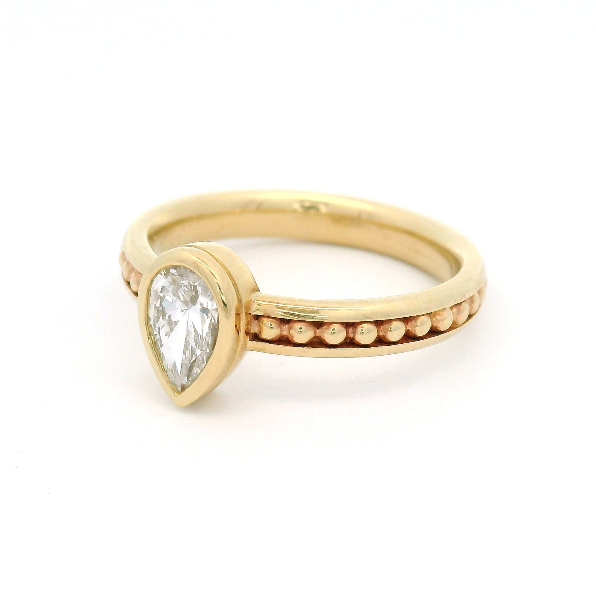 10K yellow gold solitaire engagement ring with a 0.54ct lab-grown pear-shaped diamond, delicate gold bead accents, and channel-set detailing along the band.