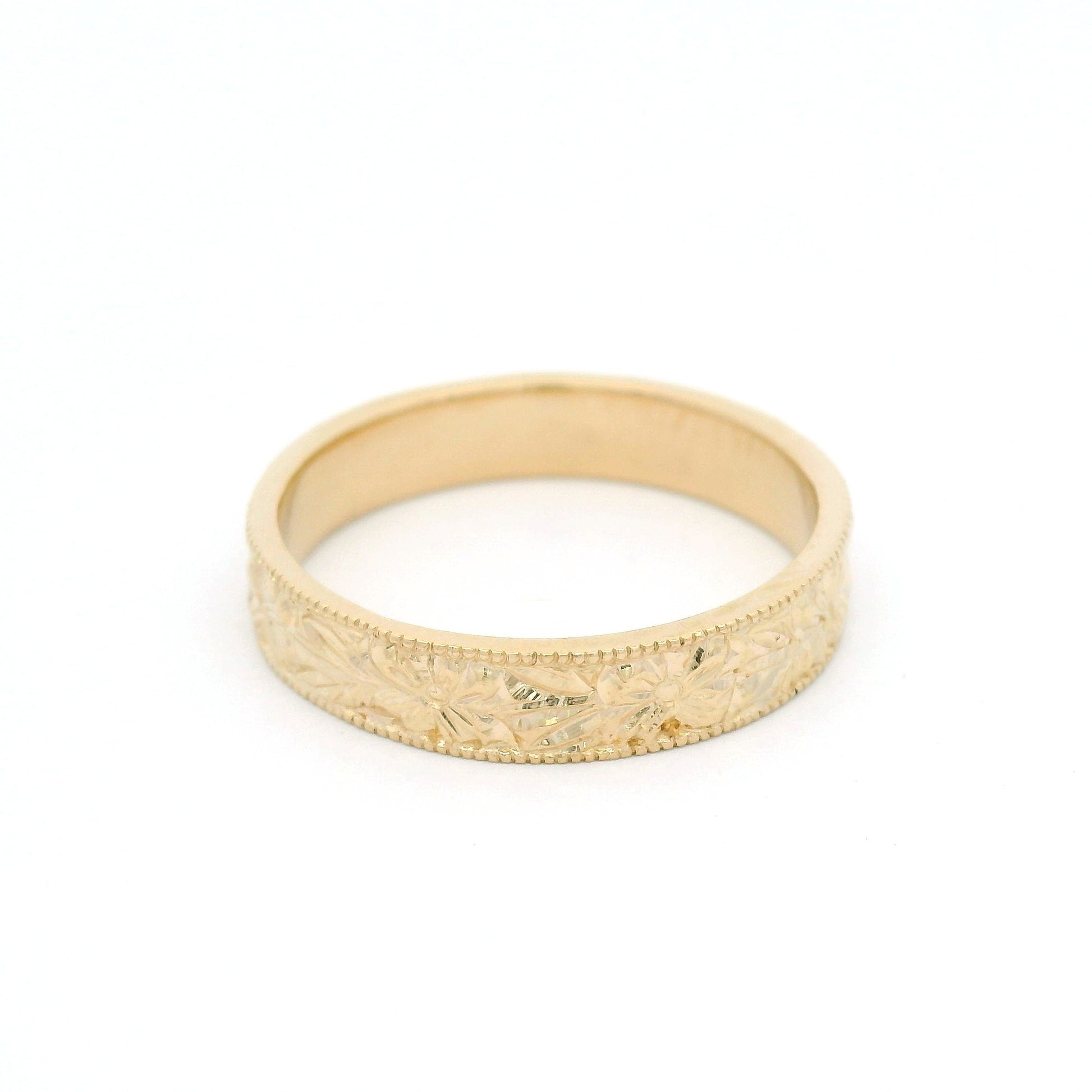 14K yellow gold 4.5mm flat profile band with hand-engraved floral pattern and milgrain edges.