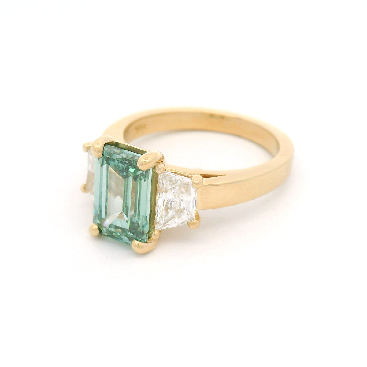 14K yellow gold three-stone engagement ring featuring a claw-set 2.50ct lab-grown green emerald-cut diamond flanked by two lab-grown trapezoid diamonds totalling 0.95cts.