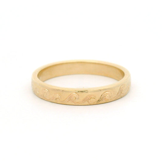 10K yellow gold 3mm wedding band with a flowing ocean wave pattern hand-engraved around three quarters of the band.
