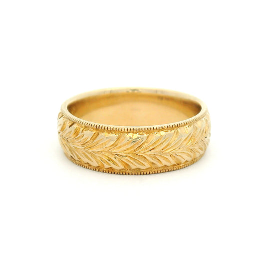 14K yellow gold 6mm wedding band featuring a hand-engraved leaf pattern and fine milgrain edges with vintage-inspired detailing.