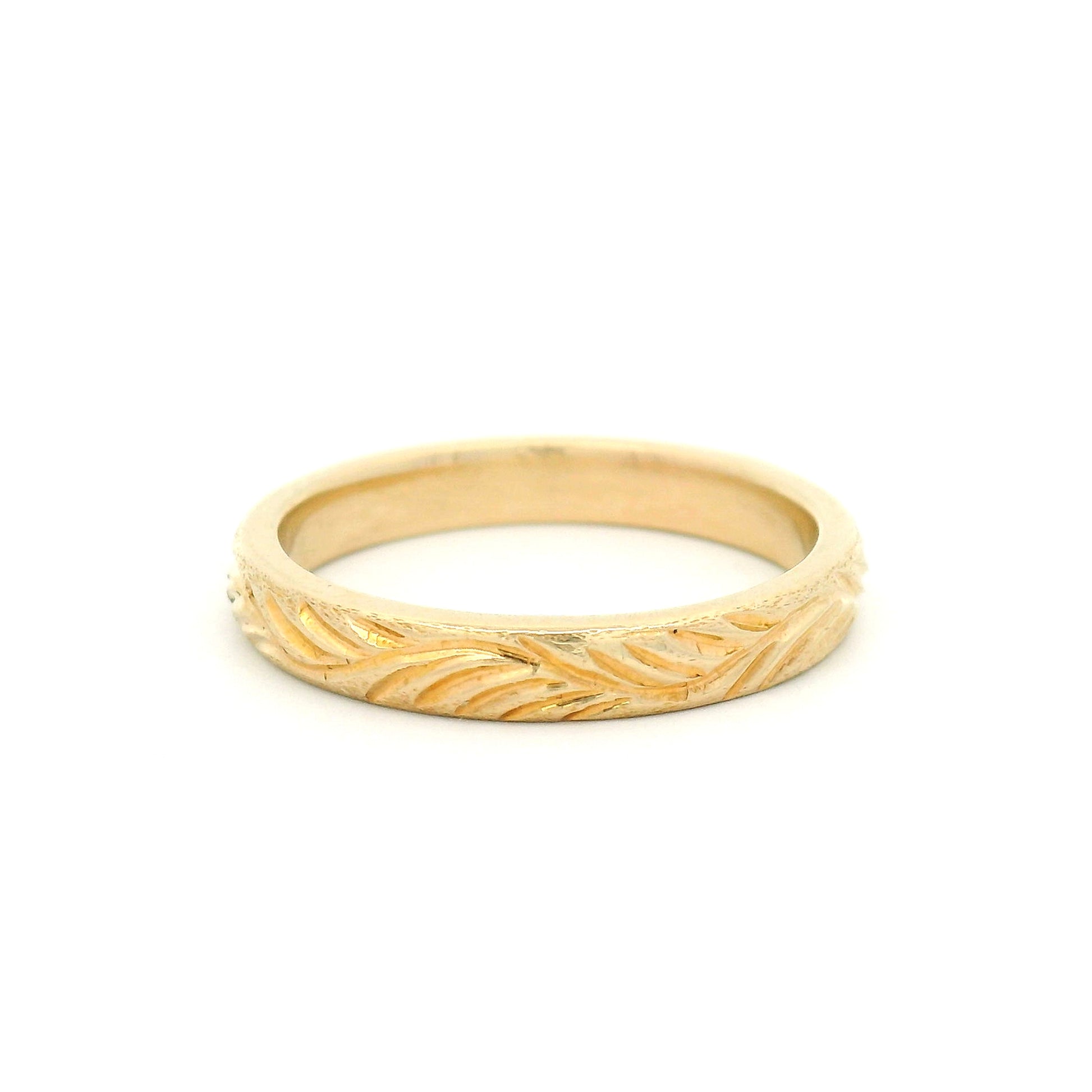 14K yellow gold 3mm soft domed wedding band featuring a hand-engraved leafy branch design with nature-inspired detailing.