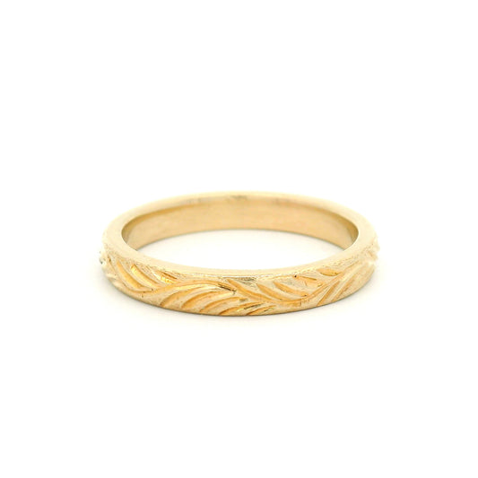 14K yellow gold 3mm soft domed wedding band featuring a hand-engraved leafy branch design with nature-inspired detailing.