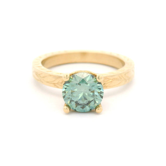 14K yellow gold solitaire engagement ring with 1.3ct lab-grown round brilliant Fancy Green diamond and hand-engraved vine and leaf pattern band.