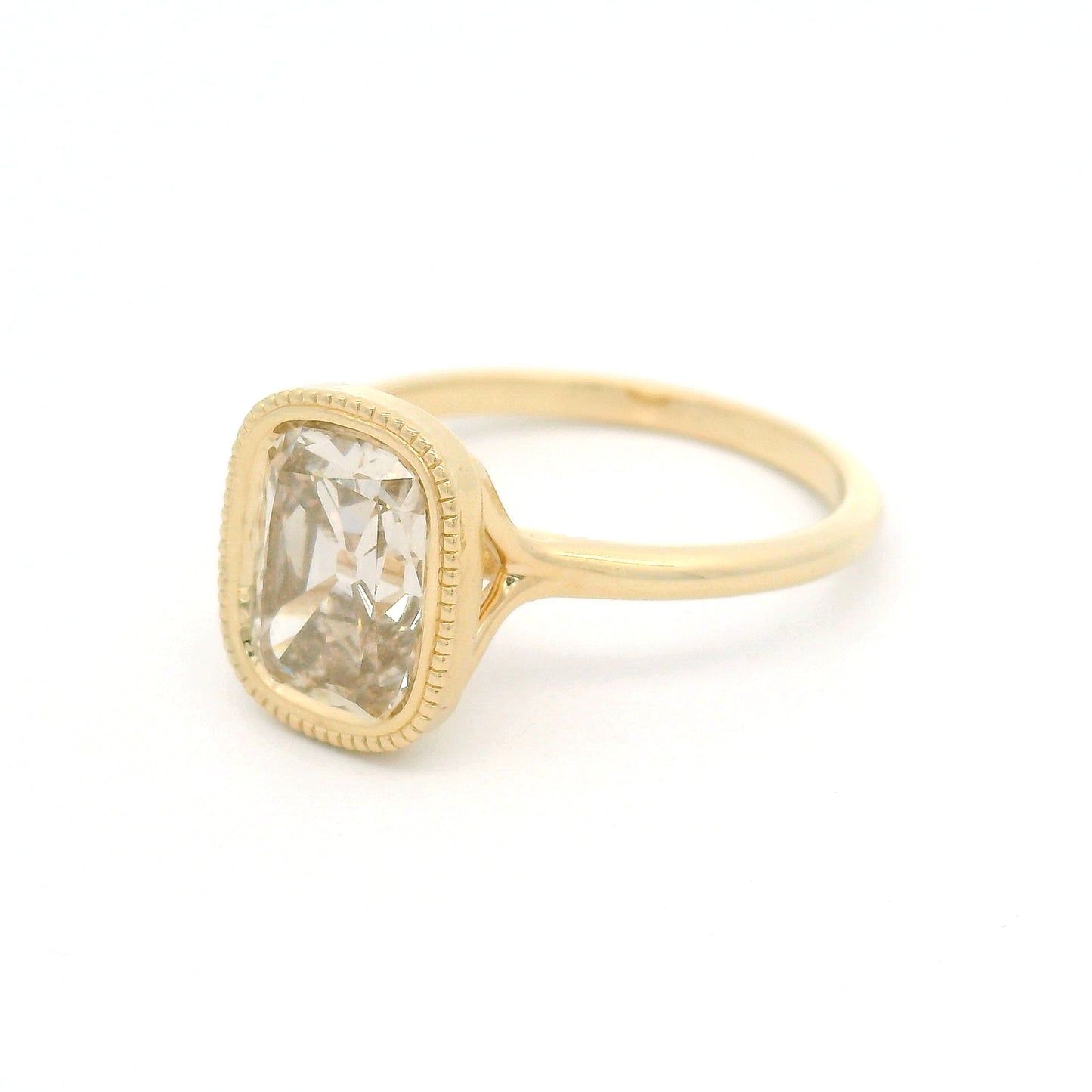 14K yellow gold solitaire engagement ring featuring a bezel-set 2.02ct lab-grown old mine-cut cushion diamond with VS2 clarity, R-S light brown colour, and a delicate milgrain edge.
