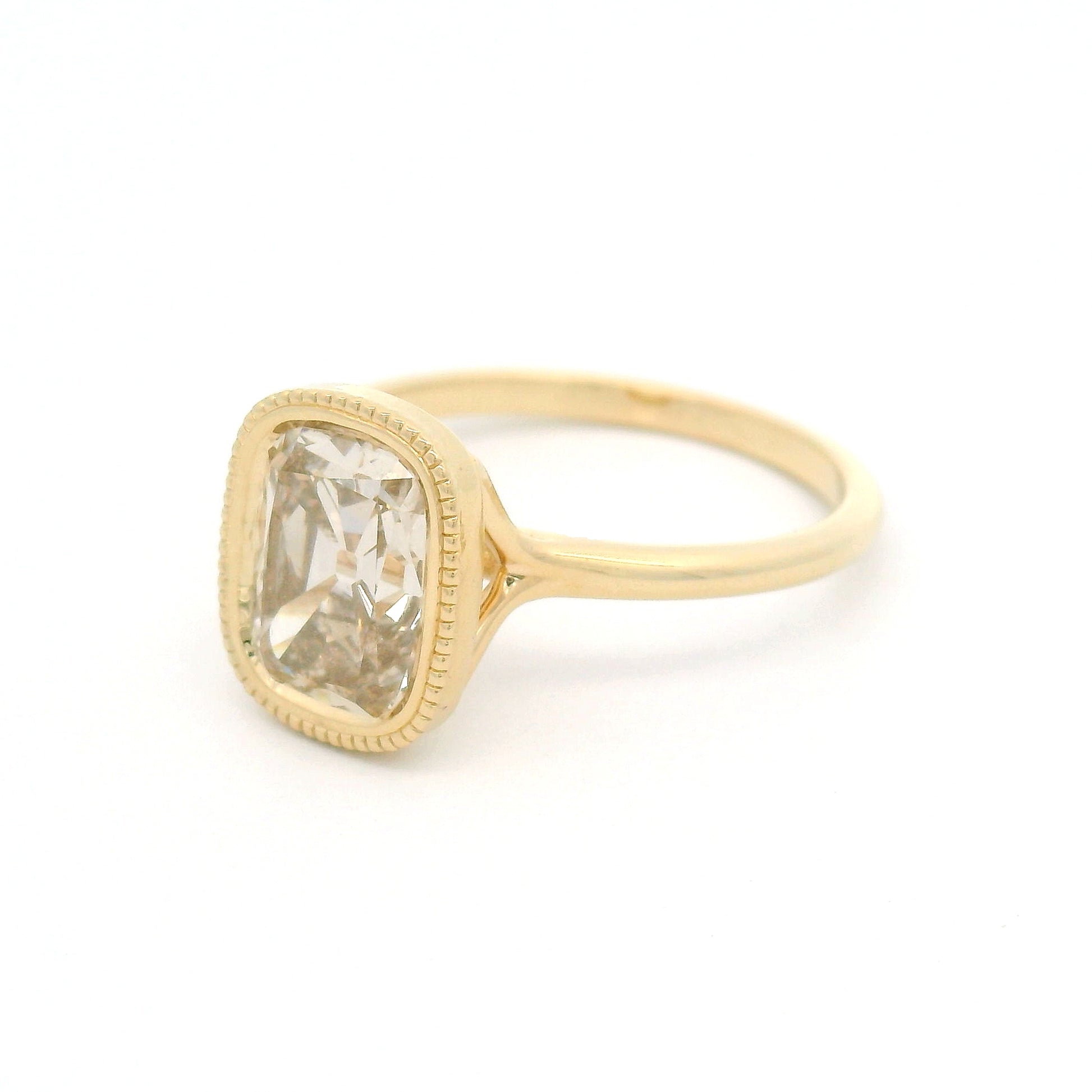14K yellow gold solitaire engagement ring featuring a bezel-set 2.02ct lab-grown old mine-cut cushion diamond with VS2 clarity, R-S light brown colour, and a delicate milgrain edge.