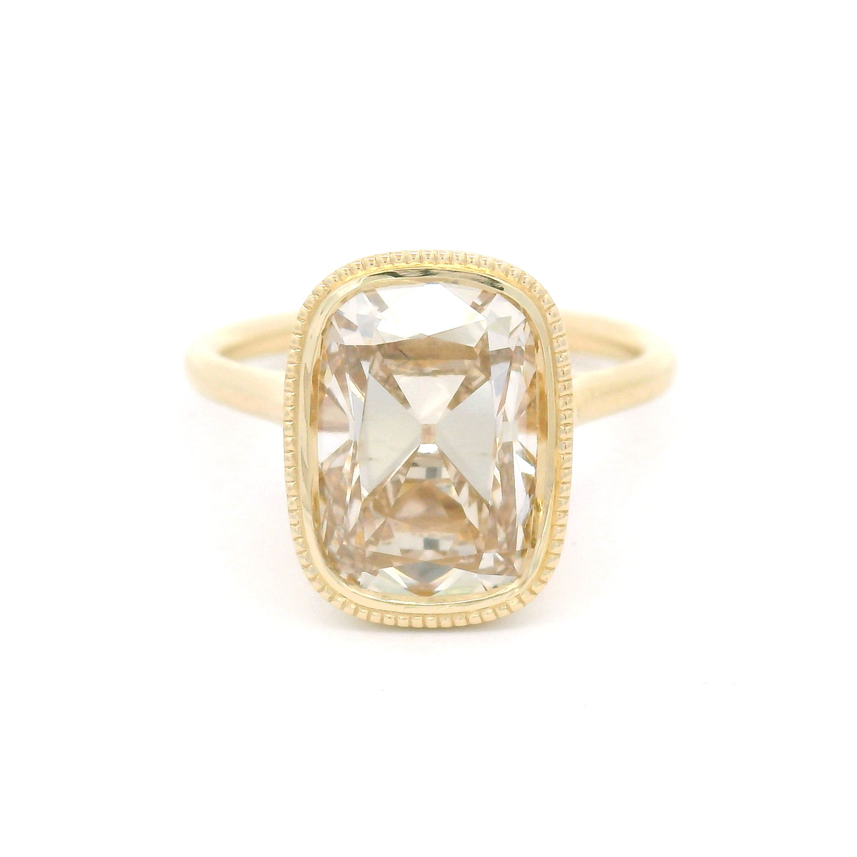 14K yellow gold bezel-set solitaire with a 4.01ct lab-grown cushion old mine-cut diamond in Fancy Light Brown, milgrain bezel and hidden leaf details.
