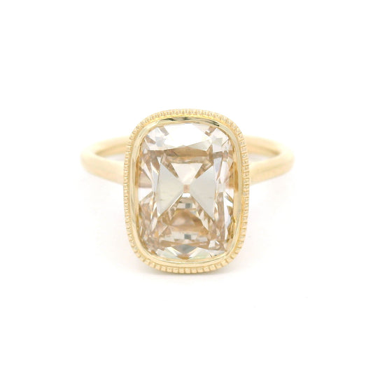 14K yellow gold bezel-set solitaire with a 4.01ct lab-grown cushion old mine-cut diamond in Fancy Light Brown, milgrain bezel and hidden leaf details.