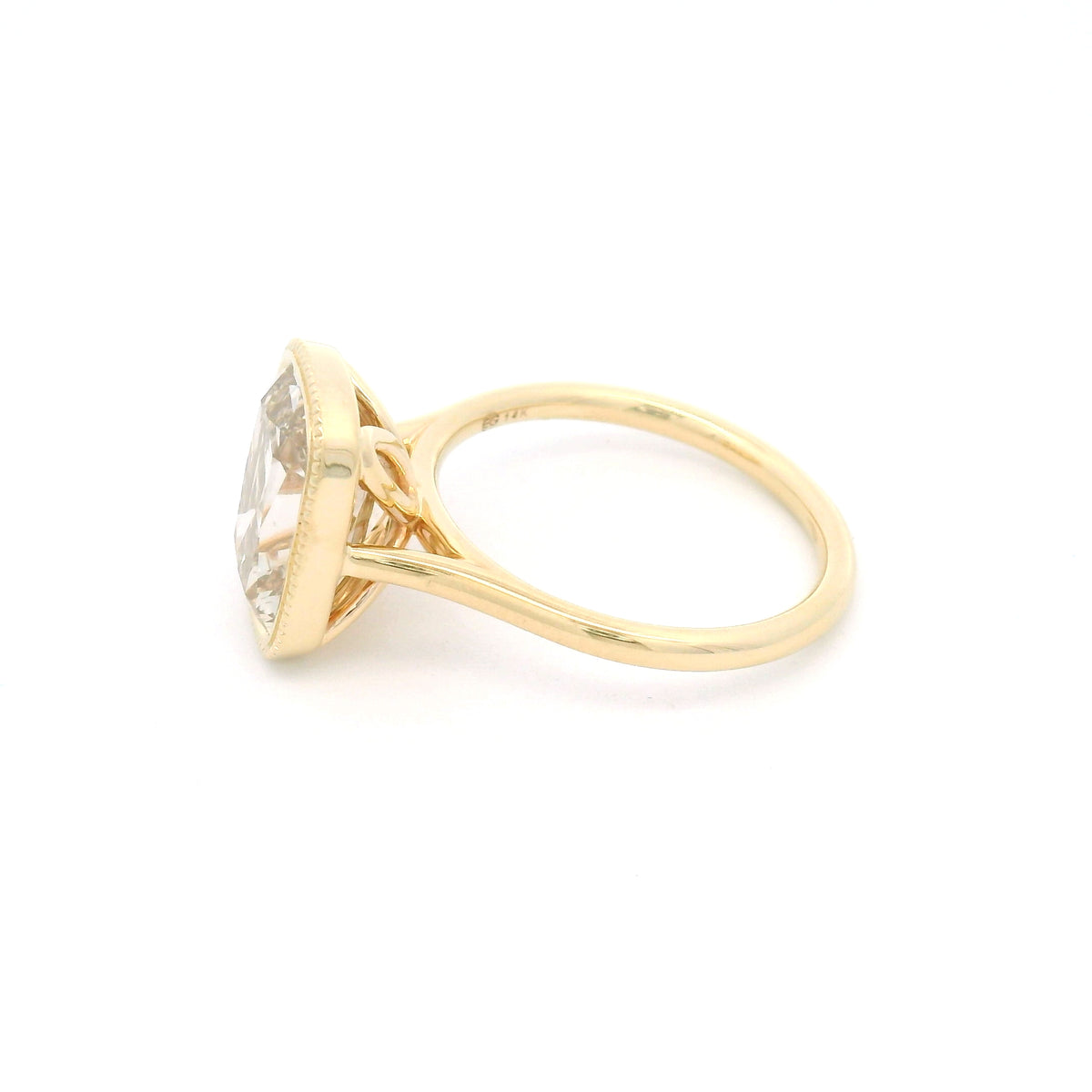 14K yellow gold bezel-set solitaire with a 4.01ct lab-grown cushion old mine-cut diamond in Fancy Light Brown, milgrain bezel and hidden leaf details.