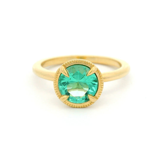 18K yellow gold solitaire ring featuring a 0.98ct round green beryl in a 4-claw setting with milgrain-framed detail on a slim band.