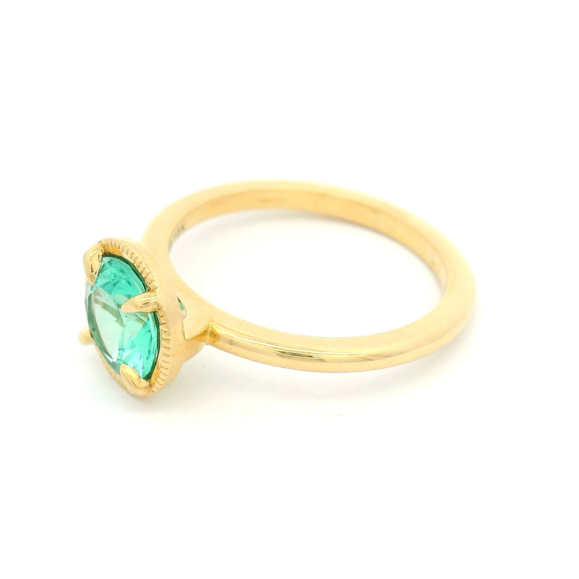 18K yellow gold solitaire ring featuring a 0.98ct round green beryl in a 4-claw setting with milgrain-framed detail on a slim band.