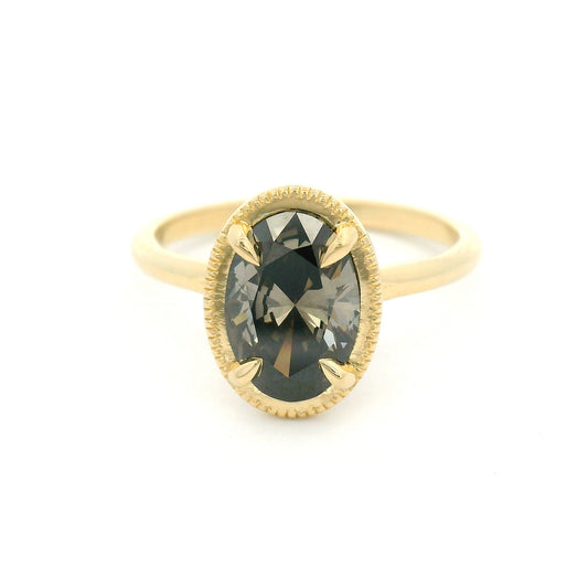 14K yellow gold solitaire engagement ring featuring a 1.55ct lab-grown oval-cut grey diamond in four-claw setting with milgrain edge and 1.8mm band.