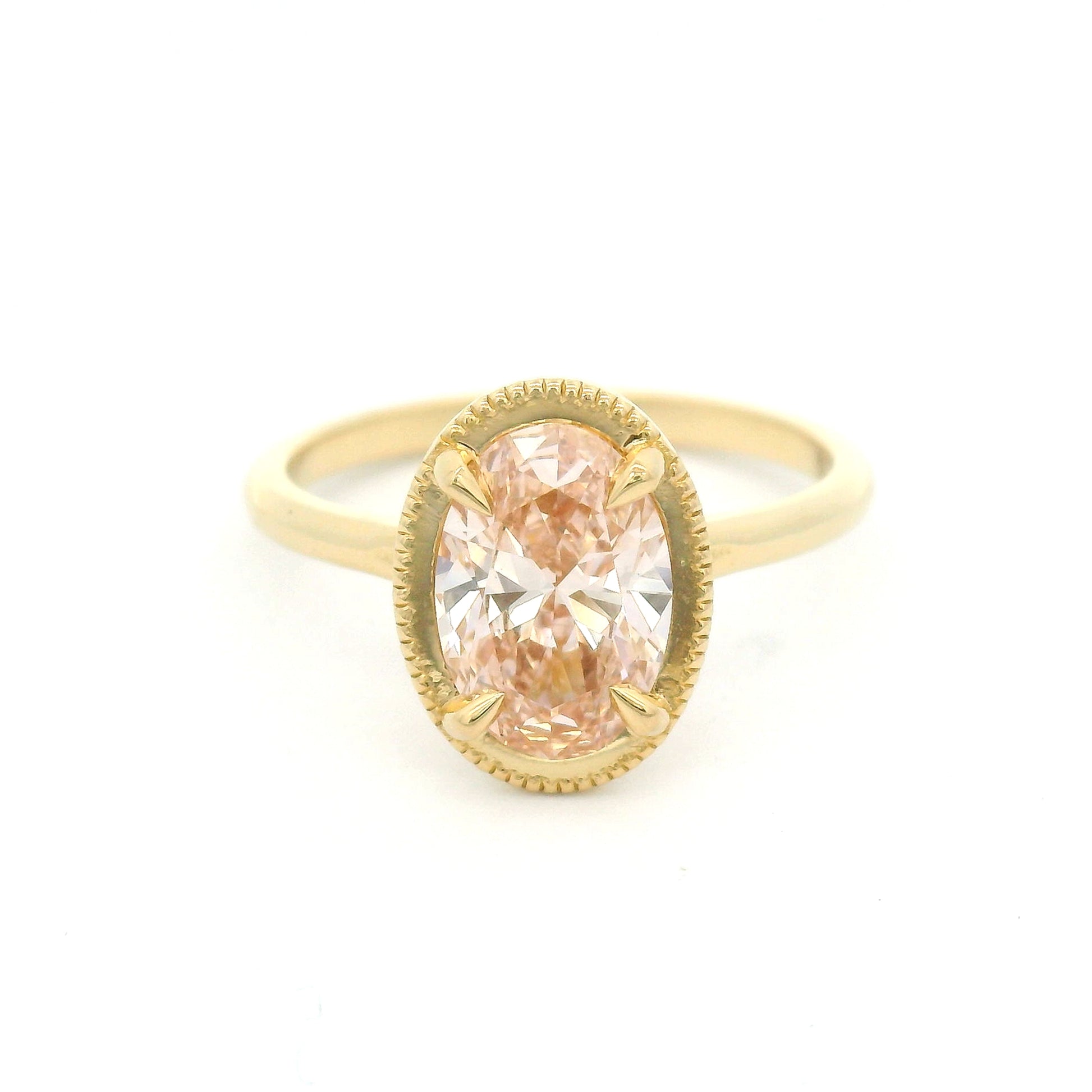 14K yellow gold solitaire engagement ring featuring a 1.50ct lab-grown oval-cut pink diamond in four-claw setting with milgrain edge and 1.8mm band.