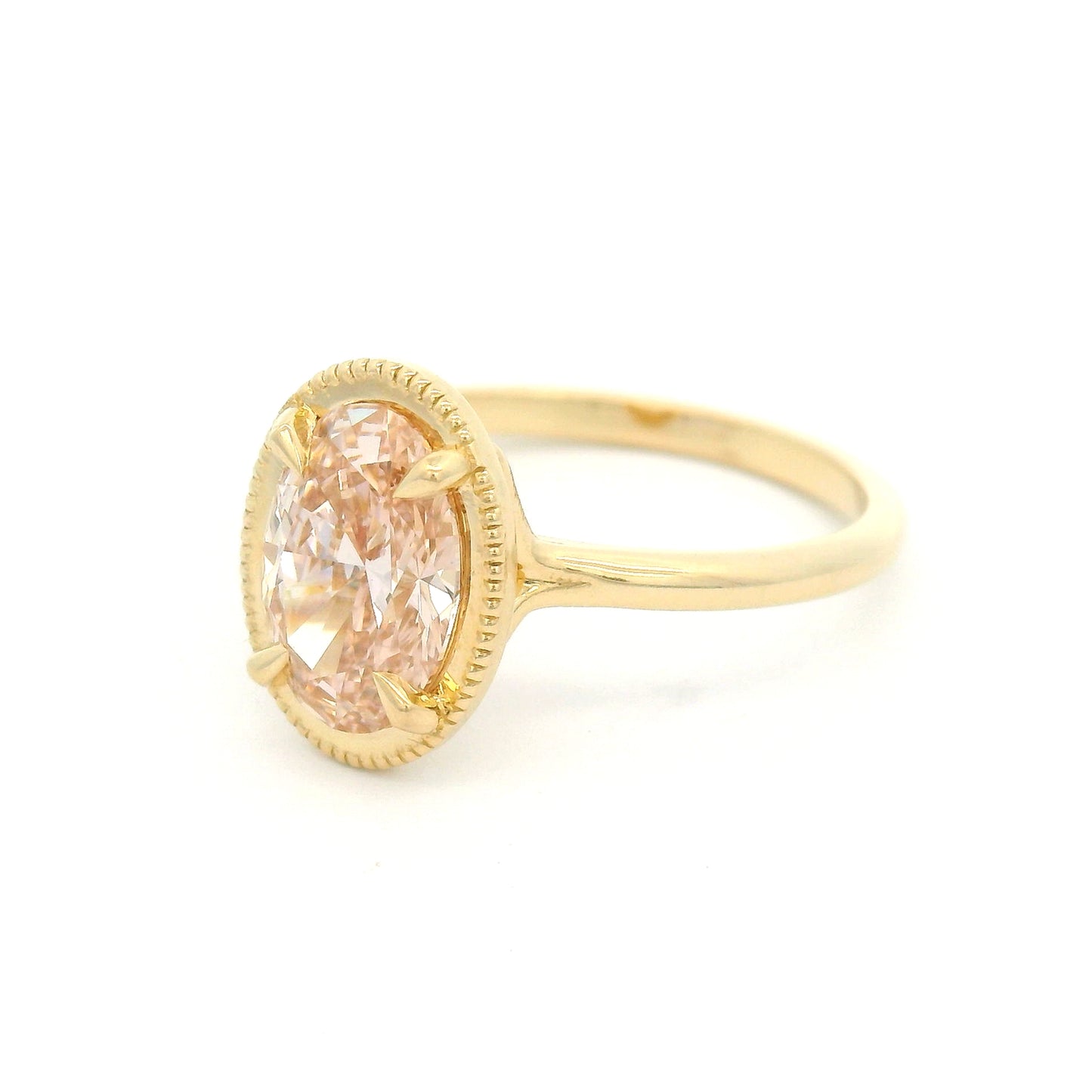 14K yellow gold solitaire engagement ring featuring a 1.50ct lab-grown oval-cut pink diamond in four-claw setting with milgrain edge and 1.8mm band.