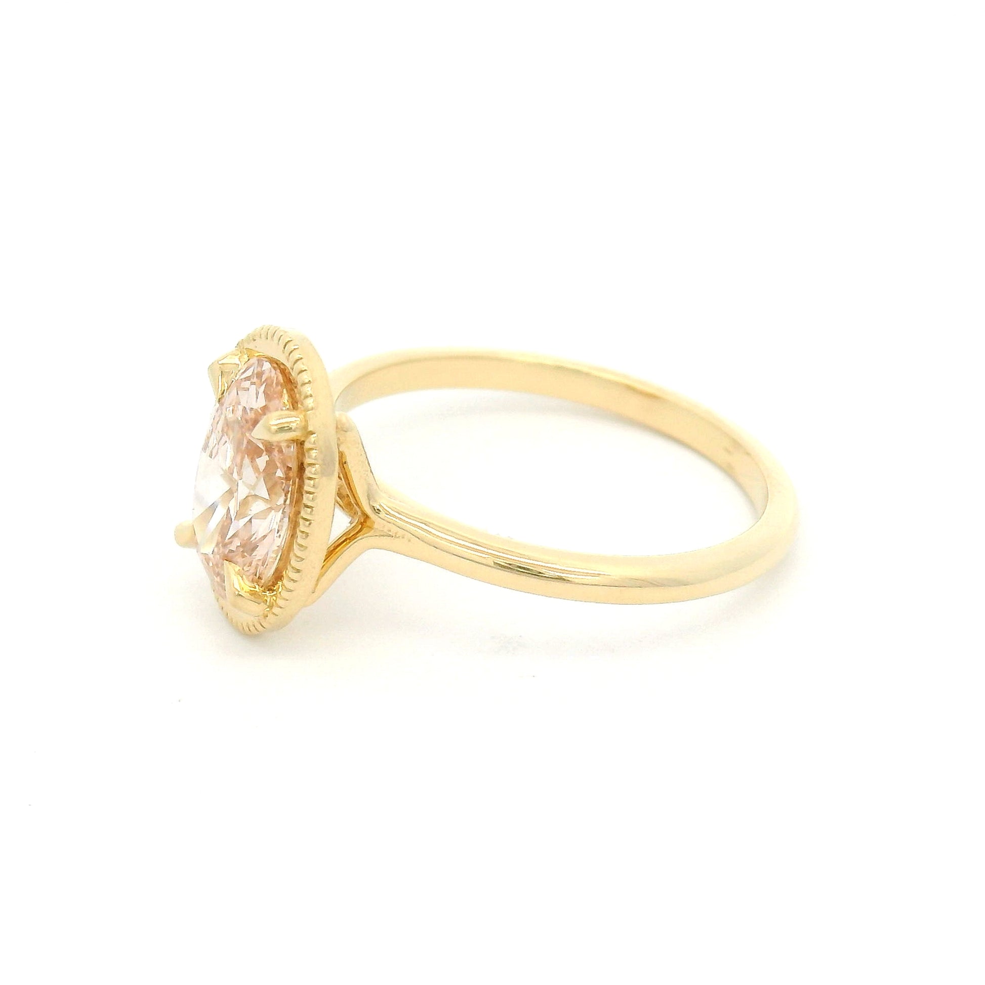 14K yellow gold solitaire engagement ring featuring a 1.50ct lab-grown oval-cut pink diamond in four-claw setting with milgrain edge and 1.8mm band.