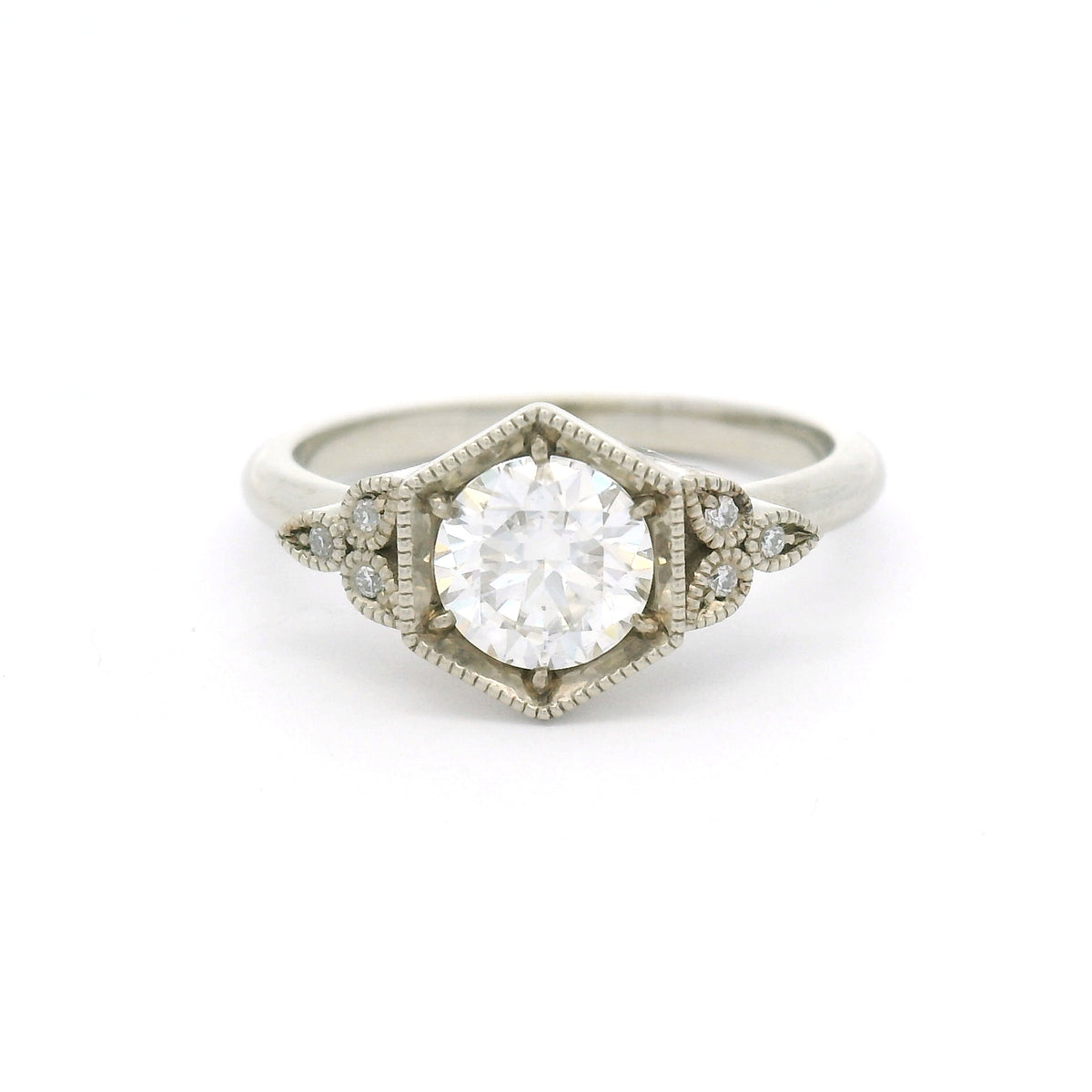 10K white gold engagement ring with a 0.75ct round brilliant-cut moissanite and six semi-bezel bead-set moissanites with milgrain details.