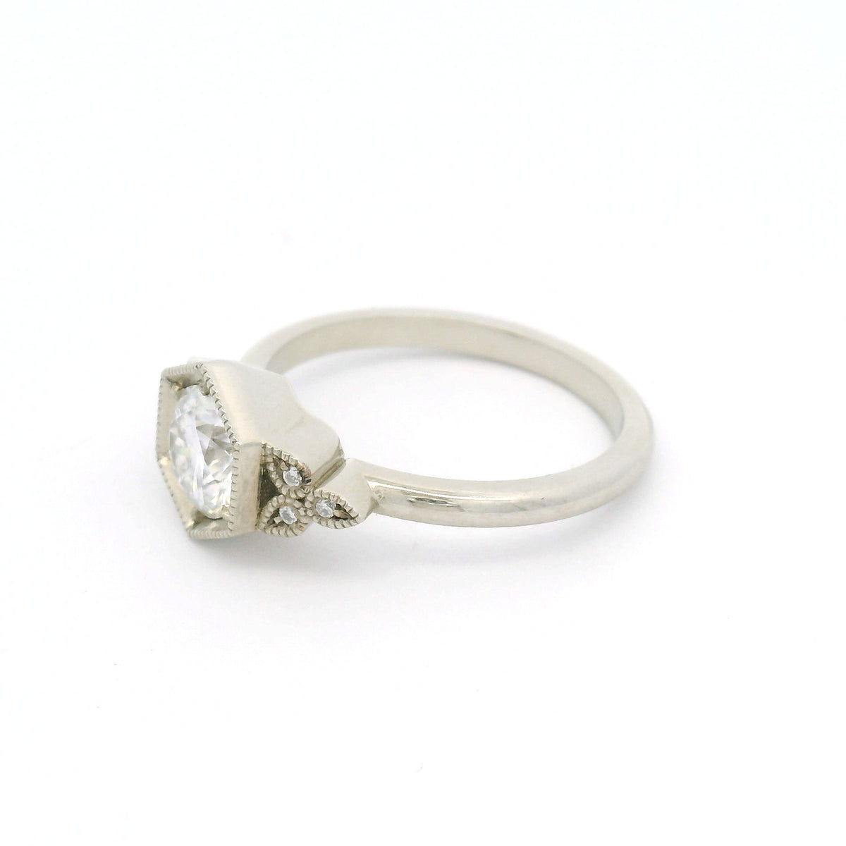 10K white gold engagement ring with a 0.75ct round brilliant-cut moissanite and six semi-bezel bead-set moissanites with milgrain details.