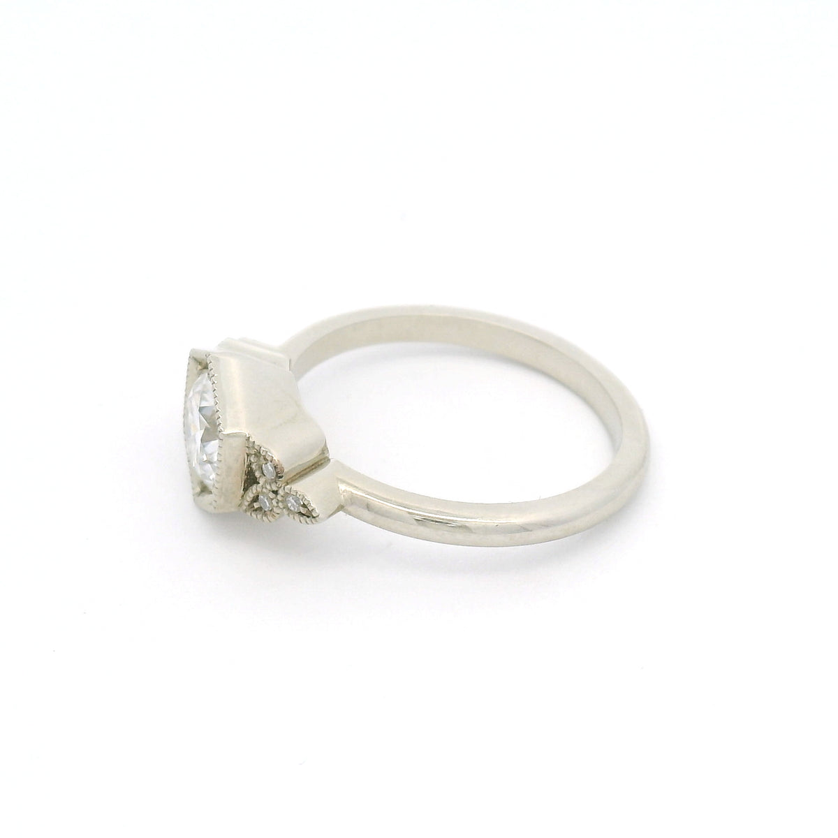 10K white gold engagement ring with a 0.75ct round brilliant-cut moissanite and six semi-bezel bead-set moissanites with milgrain details.