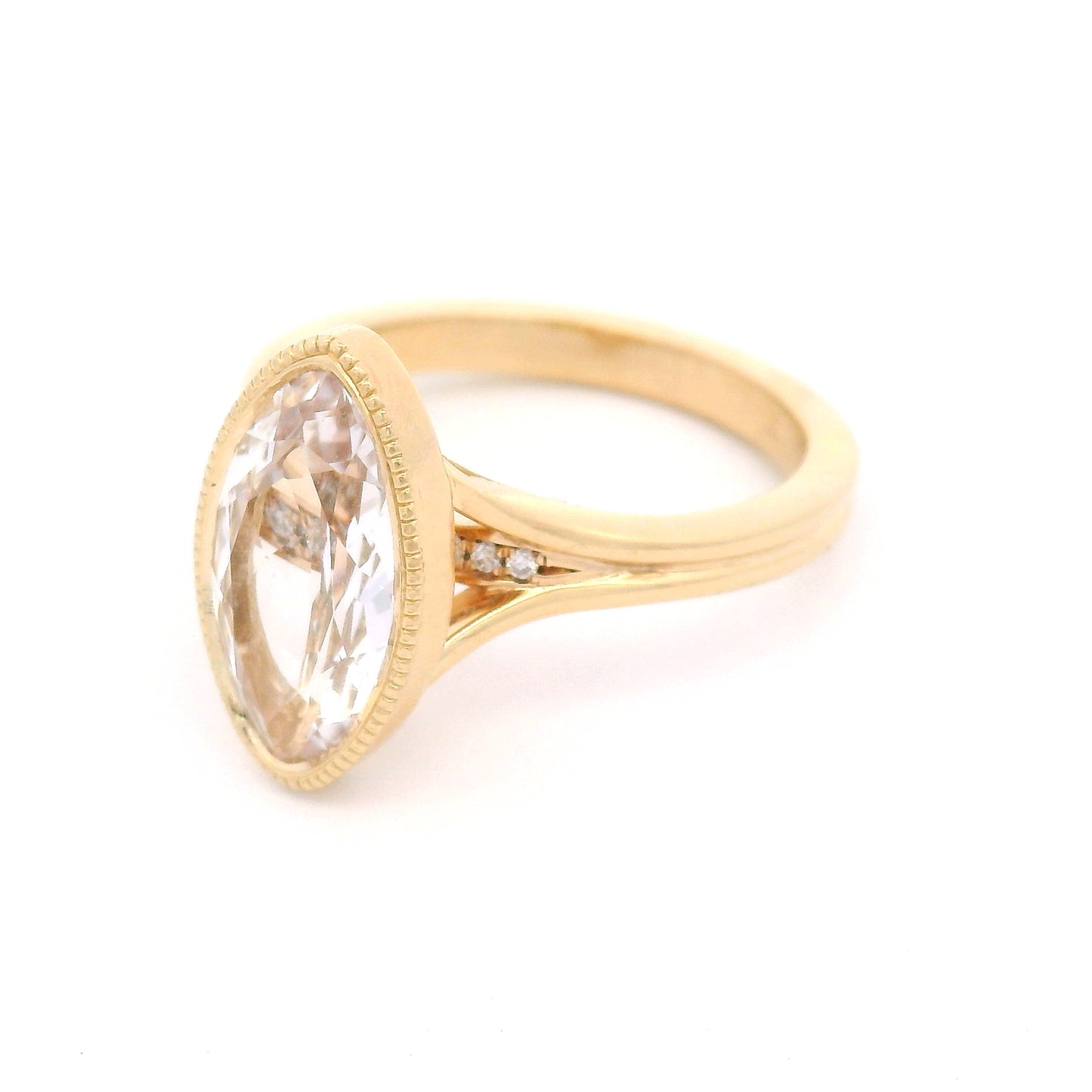14K yellow gold engagement ring featuring a 2.75ct lab-grown moval-cut white sapphire with hidden bead-set lab-grown diamond accents in the gallery.