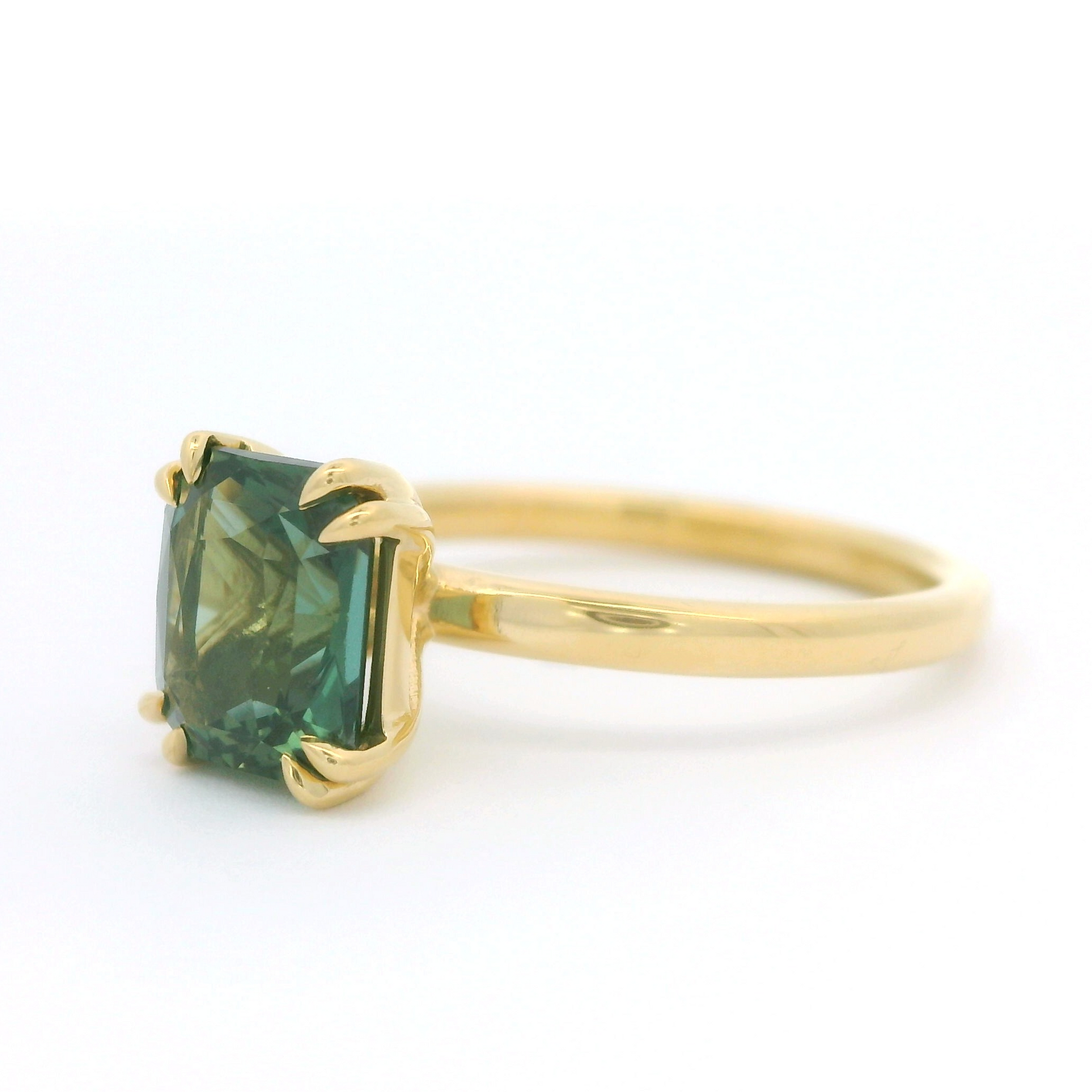 18k yellow solitaire set with a beautiful 2.10ct Teal radiant cut sapphire.  Shown from a angle.