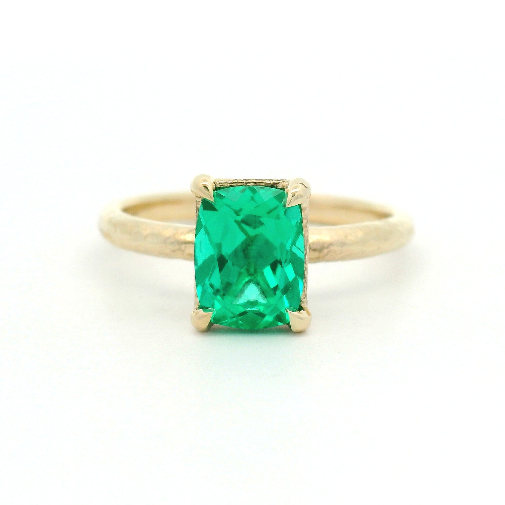 14K yellow gold organic textured solitaire engagement ring with a 1.35ct lab-grown cushion-cut emerald in a four-claw setting.