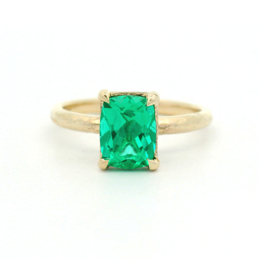 14K yellow gold organic textured solitaire engagement ring with a 1.35ct lab-grown cushion-cut emerald in a four-claw setting.