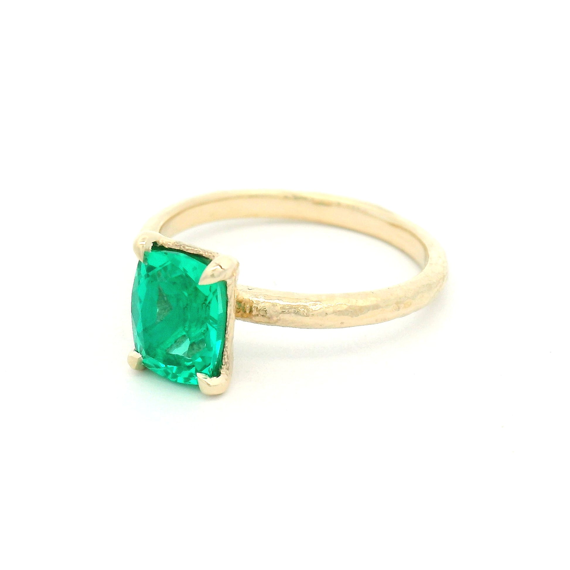 14K yellow gold organic textured solitaire engagement ring with a 1.35ct lab-grown cushion-cut emerald in a four-claw setting.