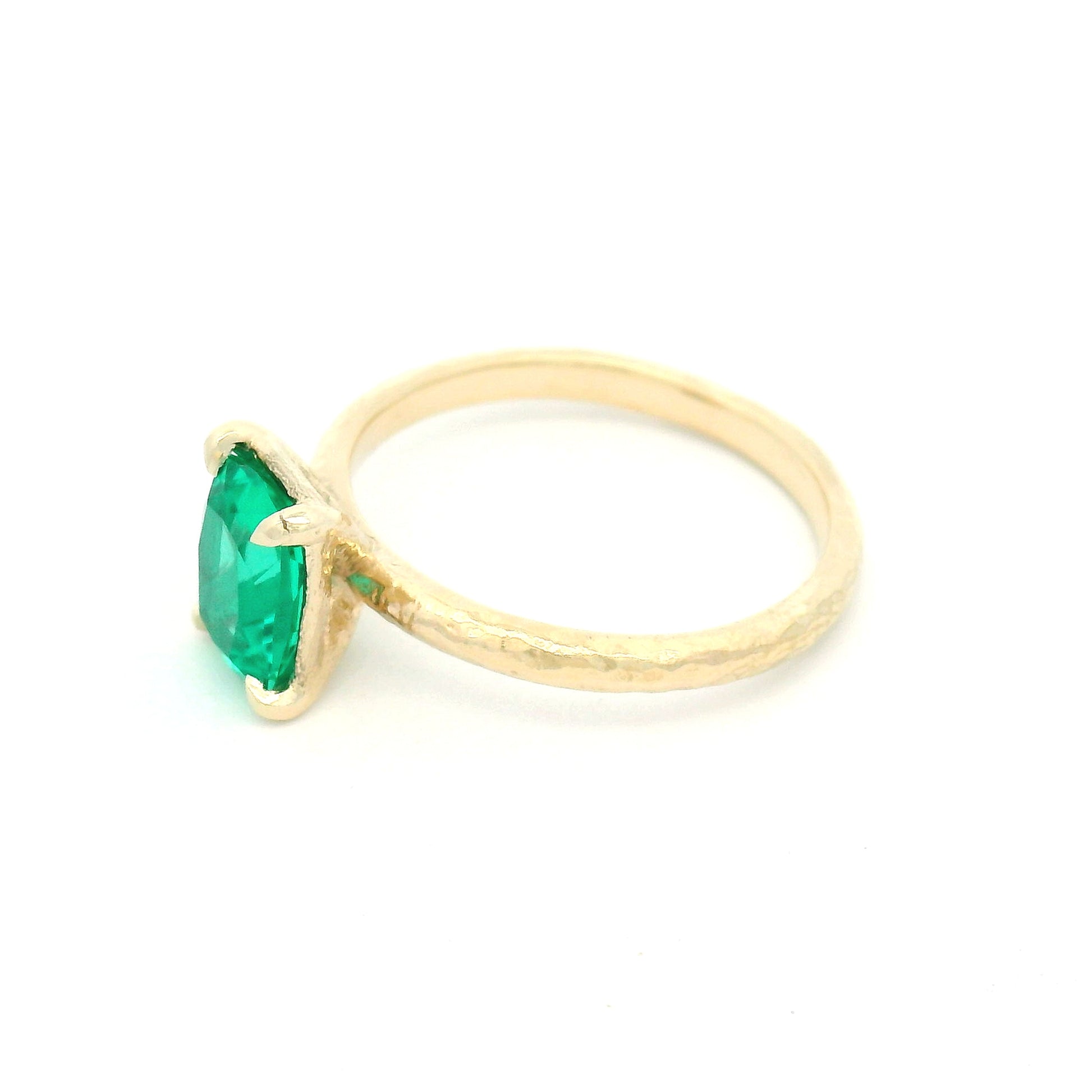 14K yellow gold organic textured solitaire engagement ring with a 1.35ct lab-grown cushion-cut emerald in a four-claw setting.