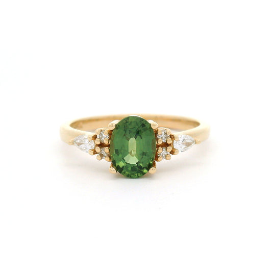 14K yellow gold engagement ring featuring a claw-set natural 1.09ct oval mixed-cut green sapphire with pear-shaped and round brilliant-cut lab-grown diamond accents on a delicate 1.8mm band.